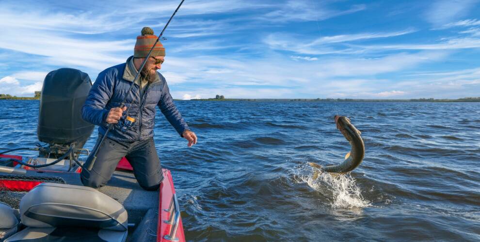 Mann angelt großen Fisch vom Boot aus